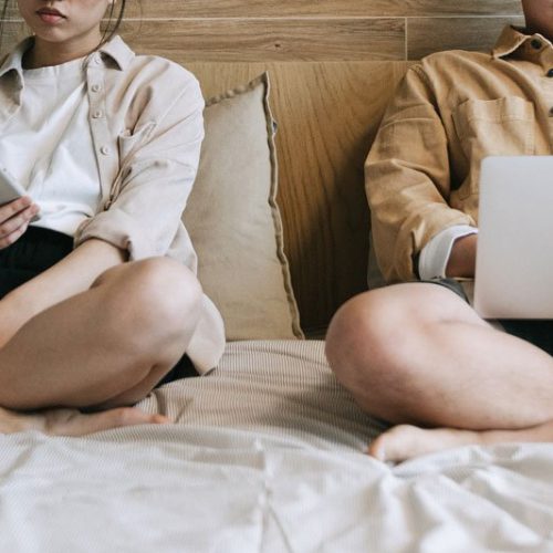 couple on technology in bed, Intimacy vs love, self-esteem therapy, Miami, FL